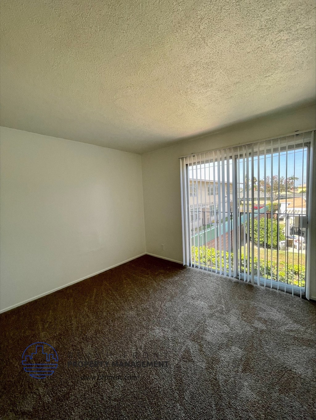 an empty living room with a sliding glass door to a balcony